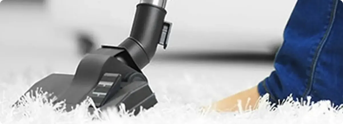 Close-up of a professional vacuuming a white carpet in Bayonne.